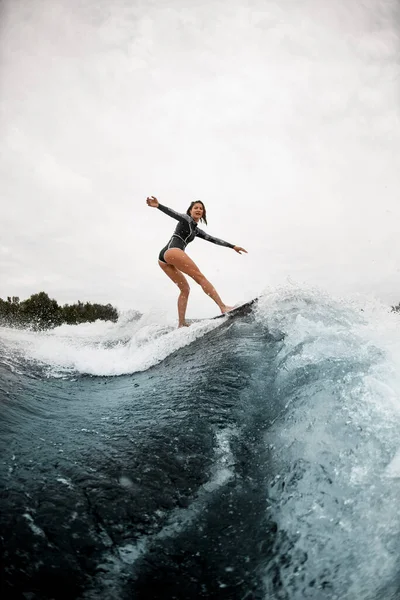 Вид на молоду спортивну жінку впевнено стоїть на дошці для серфінгу і їде на хвилі . — стокове фото