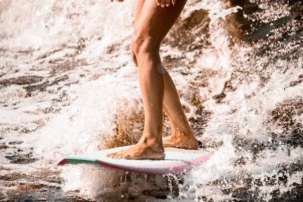 Close-up de belas pernas bronzeadas atléticas de mulher cavalgando onda no wakeboard estilo surf — Fotografia de Stock