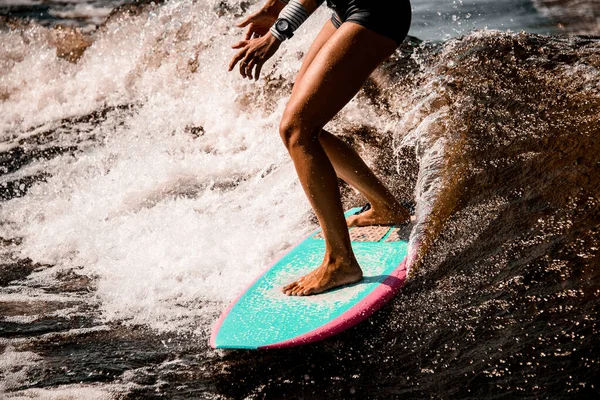 Primer plano de las piernas deportivas de la mujer joven que paseos activos ola en wakeboard estilo surf — Foto de Stock