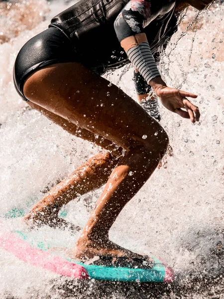 Close-up van aantrekkelijke gebruinde benen van sportieve vrouw die actief rijden op surf stijl wakeboard. — Stockfoto