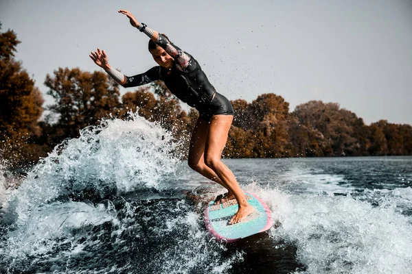 サーフィンスタイルのウェイクボードで精力的な女の子のアクティブライディング波とスプラッシュの多くを持ち上げる — ストック写真