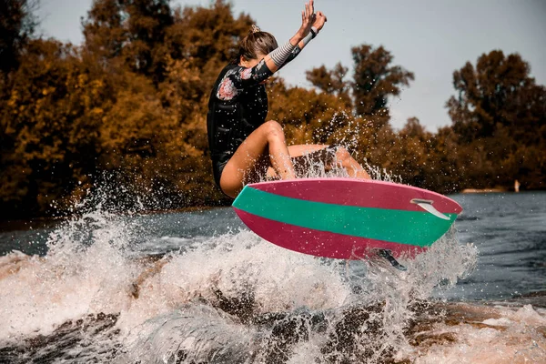 Jeune femme énergique sautant habilement par-dessus la vague sur le style de surf wakeboard — Photo