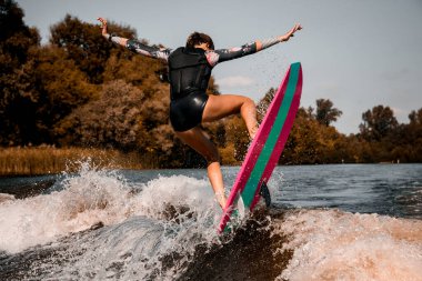 Sörf stilinde sörf tahtasında ustaca zıplayan güzel bir kadının arka planı