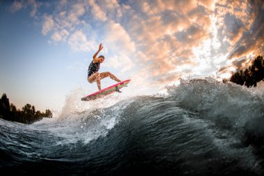 Atletik kadın ustalıkla sörf stili Wakeboard 'da büyük bir dalganın üzerinden atlıyor..