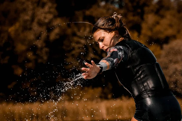 Primo piano sulla donna in muta e gilet con i capelli bagnati e spruzzi d'acqua gocce intorno — Foto Stock