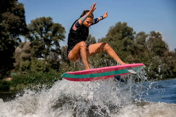 Nahaufnahme einer Frau, die gekonnt auf einer Welle auf einem Wakeboard im Surfstil springt. — Stockfoto