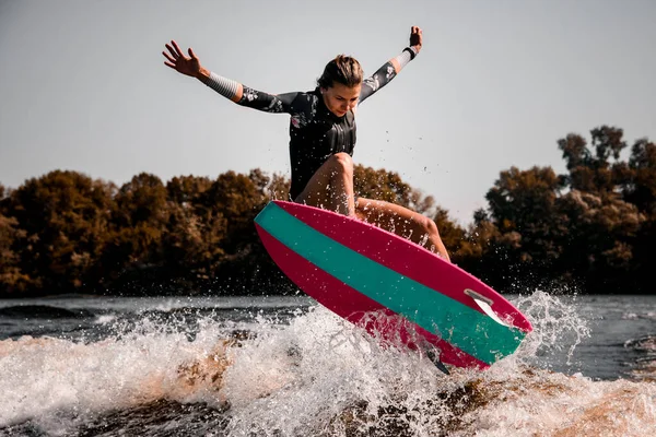 Belle jeune femme sautant habilement par-dessus les éclaboussures de vague de rivière sur le style de surf wakeboard. — Photo
