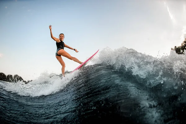 Vue latérale de la femme équilibrée sur le style de surf wakeboard sur la vague de rivière éclaboussée — Photo
