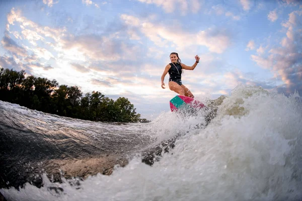 Jovem alegre fica em wakeboard estilo surf brilhante e monta grande onda salpicando — Fotografia de Stock