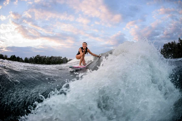 Активна жінка їде хвилею на серфінгу і торкається хвилі рукою — стокове фото