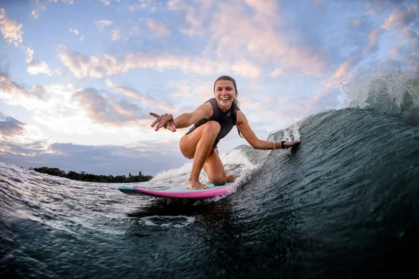 Heureux jeune femme chevauche vague sur surf style wakeboard et touche vague avec la main — Photo