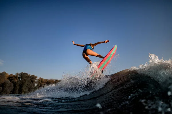 Aantrekkelijke sexy vrouw springen op Groot spetterend golf op surf stijl wakeboard. — Stockfoto