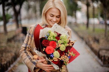 Güzel, parlak buketli, gülümseyen güzel bir kadının yakın görüntüsü.