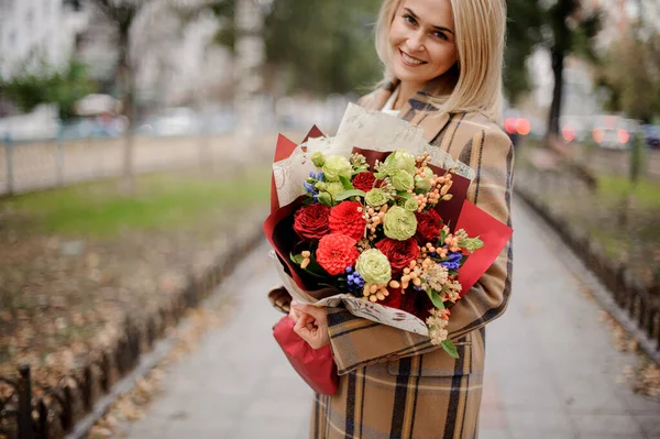 Glad leende ung kvinna i parken med bukett av ljusa blommor i händerna — Stockfoto