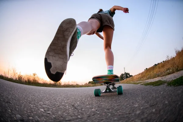 Vista angolo basso di giovane donna che cavalca sullo skateboard sull'asfalto. — Foto Stock