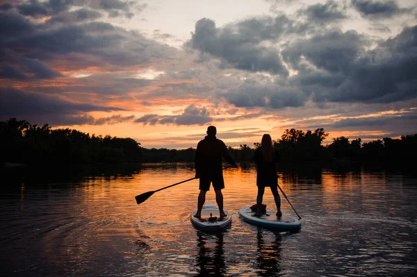 Romantic view on man and woman on sup boards floating on river — Stock Photo, Image