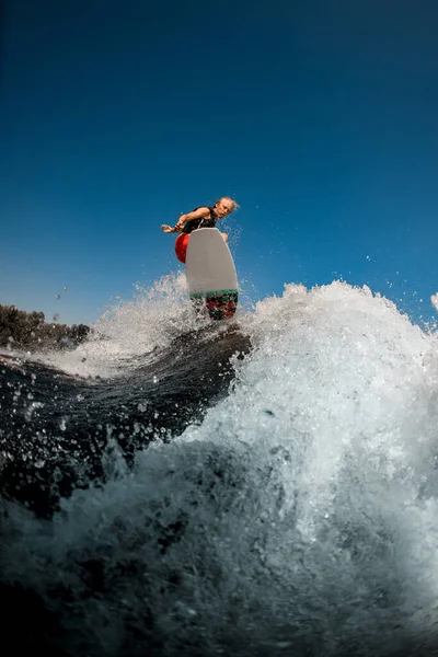 Vista del hombre saltando en el tablero por encima de la ola salpicadura —  Fotos de Stock