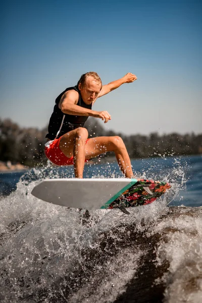 Vista de cerca del hombre en el wakeboard estilo surf magistralmente saltar sobre la ola salpicadura —  Fotos de Stock