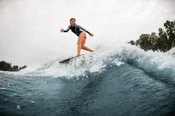 Красива спортивна жінка стоїть на дошці для серфінгу і професійно їде на хвилі — стокове фото