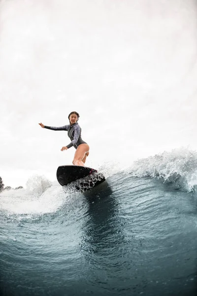Вид на жінку, яка стоїть на дошці для серфінгу і їде на хвилі — стокове фото