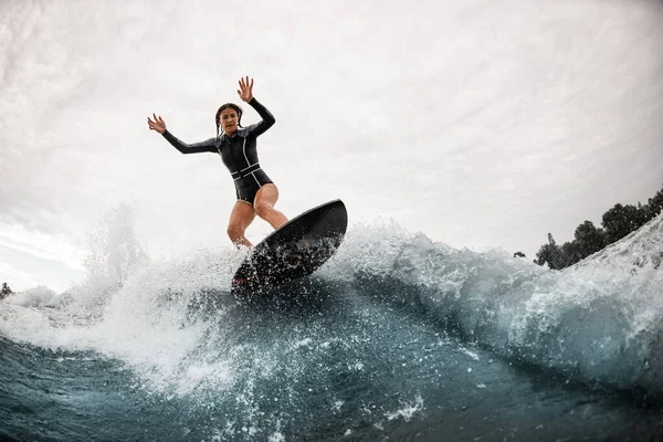 スポーティな女性はサーフボードに立ち波の上で積極的にバランスを取り — ストック写真
