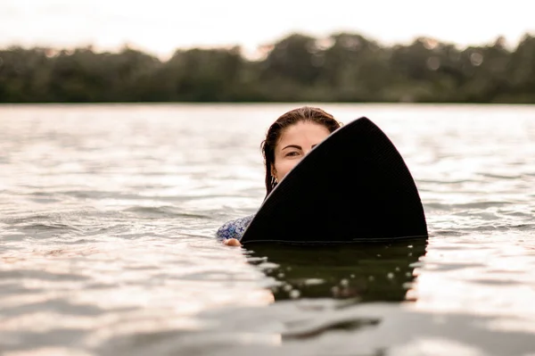 在水里的女人拿着冲浪板，从后面往外看. — 图库照片