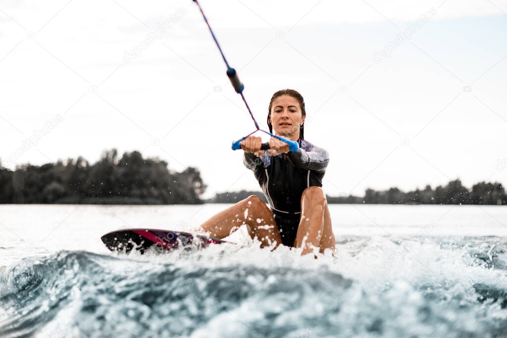 young woman holds rope in her hands and starts to get up on the board