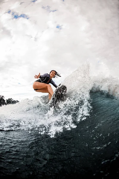 Glückliche Frau im Neoprenanzug treibt Extremsport und reitet Board auf Flusswelle — Stockfoto
