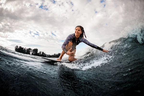波に乗ってサーフボードに座って手で水に触れる幸せな女性. — ストック写真