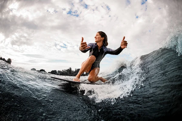 波に乗ってサーフボードに座って手のジェスチャーを見せる幸せな女性 — ストック写真
