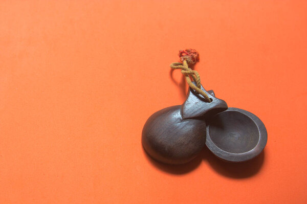 Wooden castanets typical of Spanish music, such as flamenco, las jotas, with an orange background with copy space.