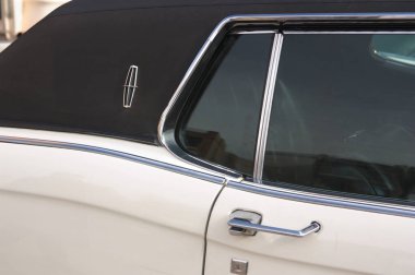 Siyah kapüşonlu eski beyaz bir arabanın pencere ve arka kapısı.