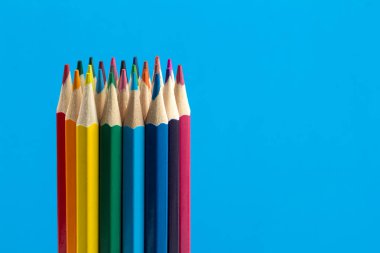 Mavi arka plan üzerinde renkli kalemler grubu