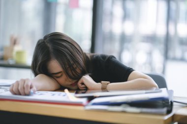 Ofisinde işyerinde uyuyan yorgun ve bitkin genç iş kadını