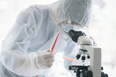 Medical scientist analyzing microscope slides in research lab for 2019-nCoV vaccine or serum.