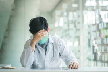 Young doctor wearing stethoscope stressed with migraine headache overworked and stress.