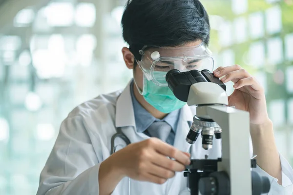 Medical scientist analyzing microscope slides in research lab for 2019-nCoV or coronavirus vaccine or serum. Health care and medical services concept.