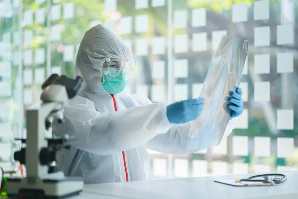 Koruyucu kıyafetli bir doktor, koğuş hastanesindeki hastanın göğüs röntgenini kontrol ediyor. Corona virüsü Covid-19 Kavramı.