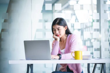 Young Asian graphic designer working on computor and graphics tablet in her working space. Young college students working in the library.