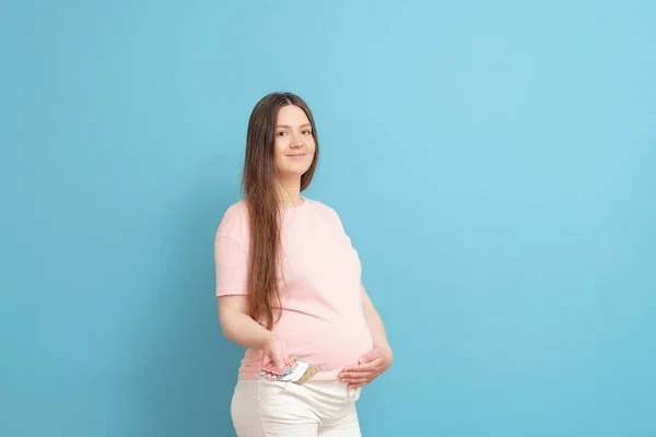 Genç Güzel Hamile Bir Kadın Mavi Arka Planda Elinde Haplar — Stok fotoğraf