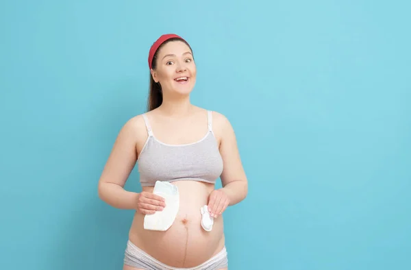 Feliz Joven Embarazada Sobre Fondo Azul Con Pañales Calcetines Blancos — Foto de Stock