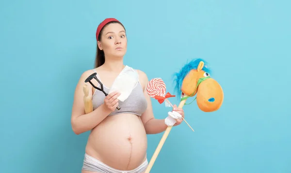 Sorprendida Joven Embarazada Sobre Fondo Azul Sosteniendo Juguetes Pañales Aparatos — Foto de Stock