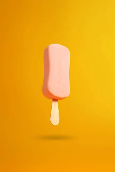 노란색 배경에 공중에 매달려 분홍색 아이스크림 — 스톡 사진