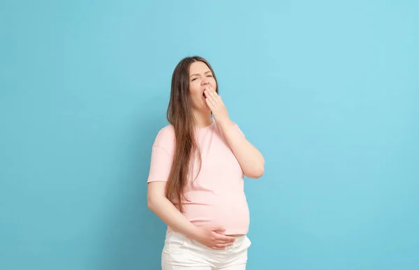 Mavi Arka Planda Pembe Elbiseli Uykulu Hamile Kadın — Stok fotoğraf