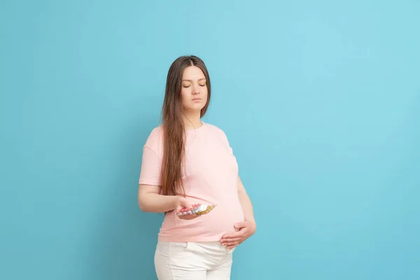 Młoda Piękna Kobieta Ciąży Niebieskim Tle Trzymając Tabletki Ręku — Zdjęcie stockowe