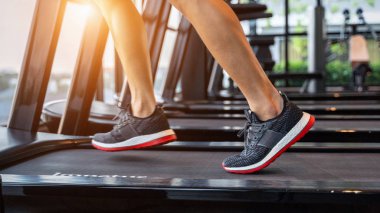 Spor salonundaki koşu bandında koşan spor ayakkabılı bir erkek. Egzersiz konsepti.