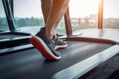 Spor salonundaki koşu bandında koşan spor ayakkabılı bir erkek. Egzersiz konsepti.