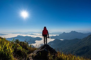 Fotoğrafçının eli kamerayı tutuyor ve doğada kayanın üstünde duruyor. Seyahat kavramı.