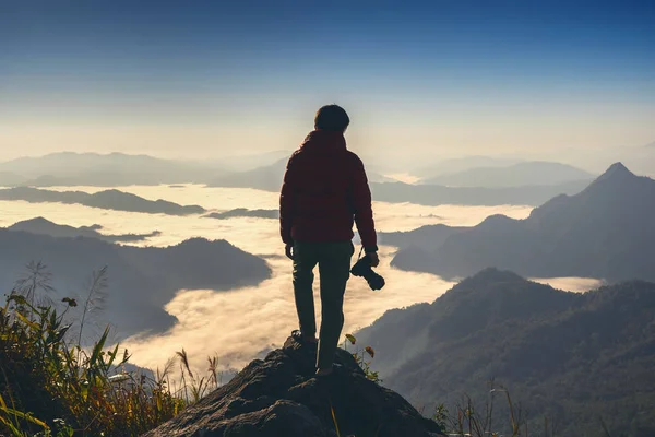 Φωτογράφος χέρι κρατώντας φωτογραφική μηχανή και στέκεται στην κορυφή του βράχου στη φύση. Ταξιδιωτική έννοια. — Φωτογραφία Αρχείου