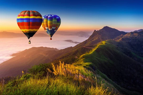 Landschaft aus Morgennebel und Bergen mit Heißluftballons bei Sonnenaufgang. — Stockfoto